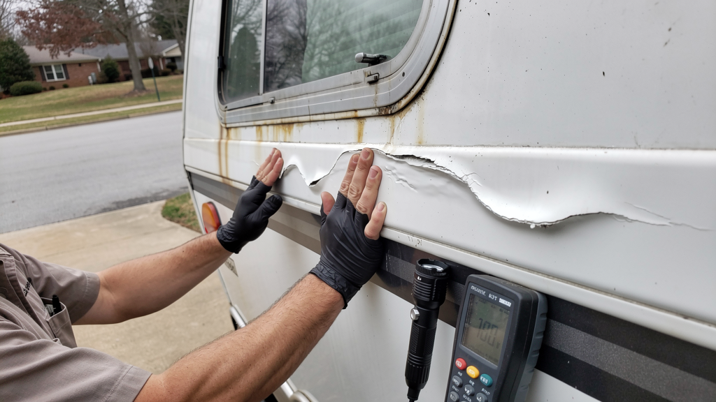 Technician inspecting a bubbled fiberglass RV sidewall