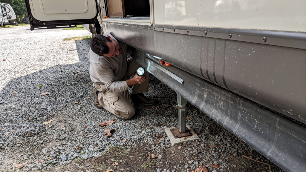 Technician inspecting the lower rail and seal of an RV slide-out