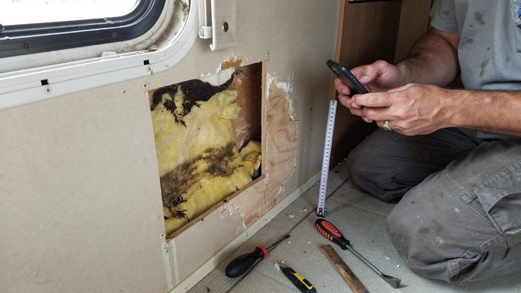 Open RV wall section showing damp insulation and damaged wood